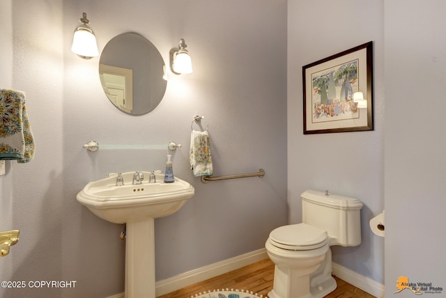 bathroom featuring wood finished floors, toilet, baseboards, and a sink