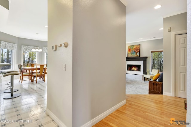 hall with baseboards, a chandelier, crown molding, and recessed lighting