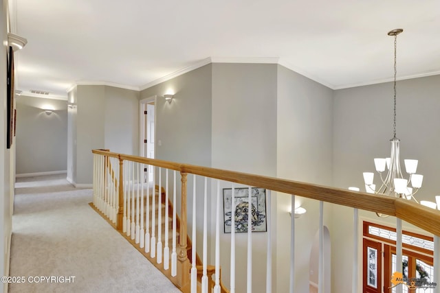 hall with a chandelier, carpet, ornamental molding, an upstairs landing, and baseboards