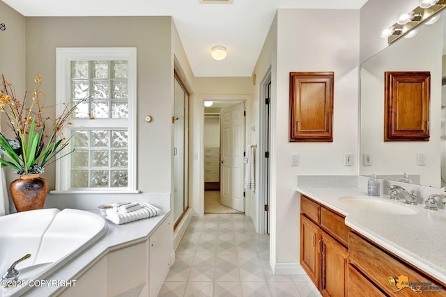 full bath with tile patterned floors, vanity, a garden tub, baseboards, and a walk in closet