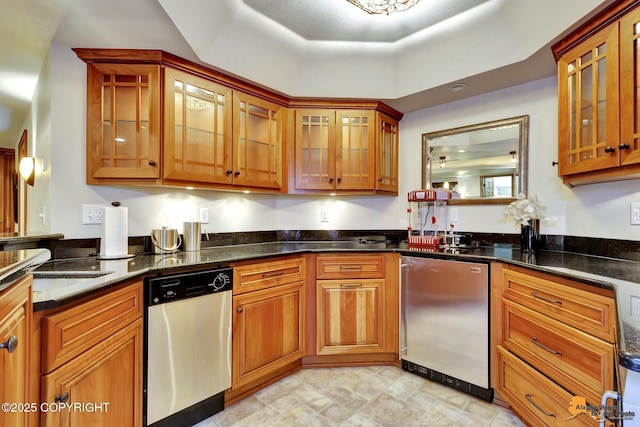 kitchen featuring stainless steel appliances, brown cabinets, and dark stone counters