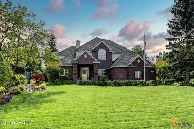 traditional-style home featuring a front yard, brick siding, and a chimney