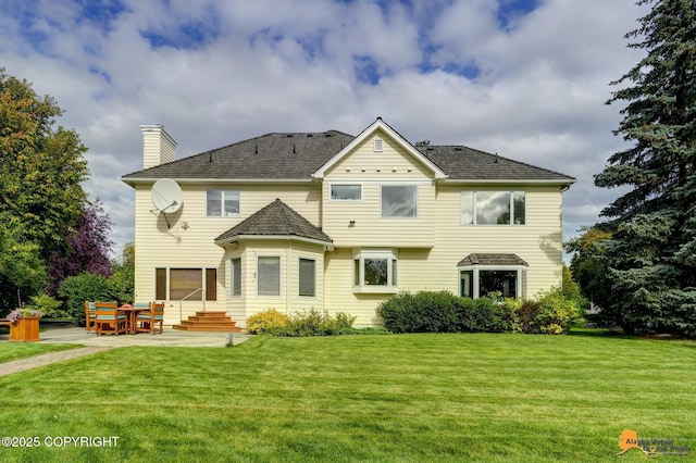rear view of house with a chimney, a lawn, and a patio area