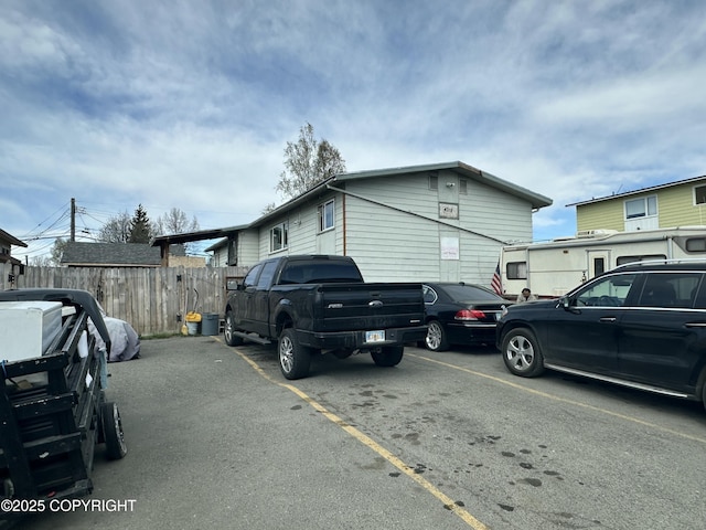 view of property exterior with fence and uncovered parking