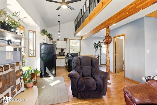 living area with light wood-style flooring, ceiling fan, vaulted ceiling, and baseboards