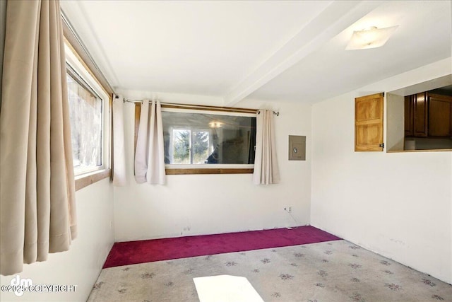 carpeted empty room with beam ceiling