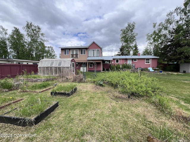 7700 Dover Ave, Anchorage, AK 99504 - back of property featuring a greenhouse, a vegetable garden, and an outbuilding