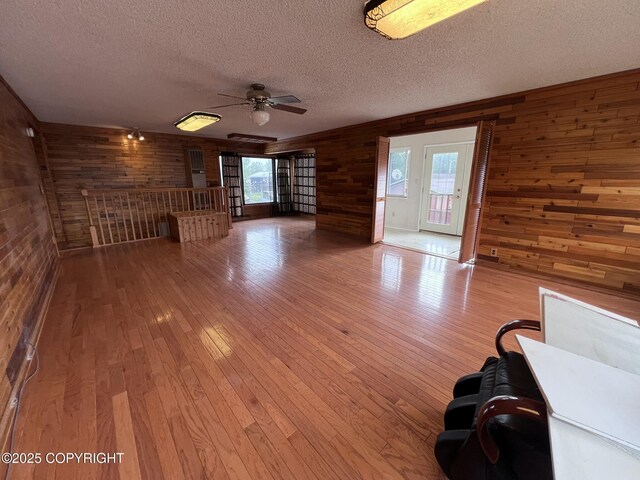 7700 Dover Ave, Anchorage, AK 99504 - unfurnished living room featuring wood walls, ceiling fan, a textured ceiling, and wood-type flooring