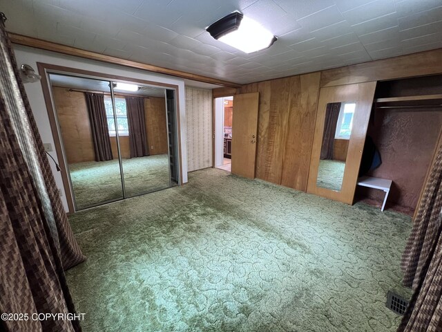 7700 Dover Ave, Anchorage, AK 99504 - unfurnished bedroom featuring carpet floors, wooden walls, and two closets