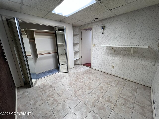 7700 Dover Ave, Anchorage, AK 99504 - unfurnished bedroom with a drop ceiling, wallpapered walls, a closet, and tile patterned flooring