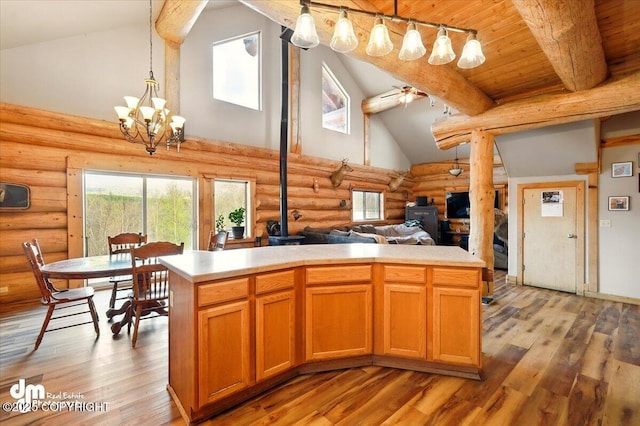 kitchen featuring a wood stove, rustic walls, high vaulted ceiling, light wood-type flooring, and light countertops