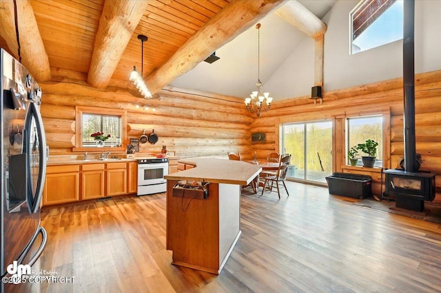 kitchen with stainless steel fridge with ice dispenser, white electric range oven, a wood stove, light wood-type flooring, and light countertops