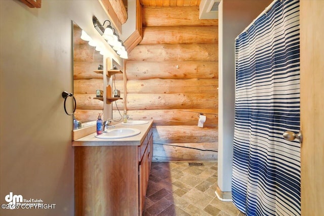 full bathroom featuring log walls, stone finish flooring, and double vanity