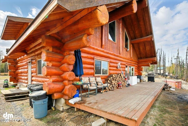 rear view of house with log exterior and a wooden deck