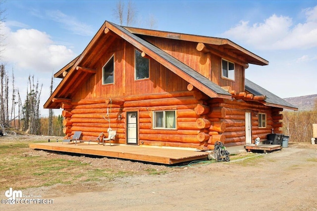 rear view of house with log exterior and a wooden deck