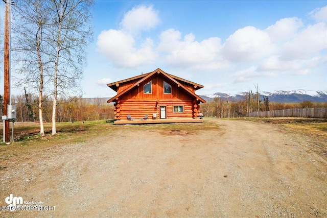 view of front of home with log exterior, driveway, and a deck with mountain view