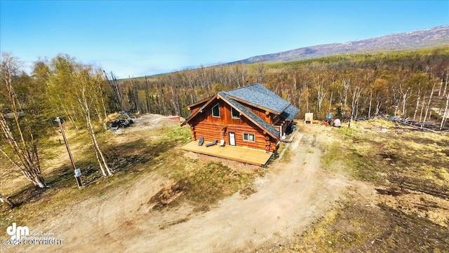 aerial view of property and surrounding area with a heavily wooded area and a mountain backdrop