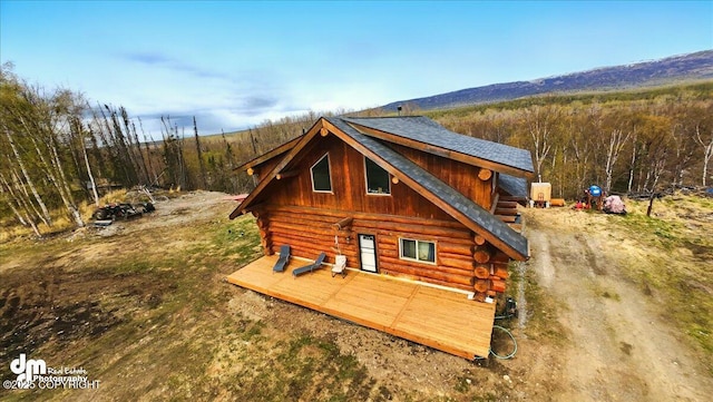 view of property exterior featuring log siding, a wooden deck, and a shingled roof