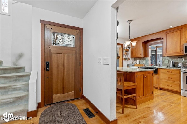 10613 Washington Cir, Anchorage, AK 99515 - entryway featuring light wood-style floors, healthy amount of natural light, stairway, and a chandelier