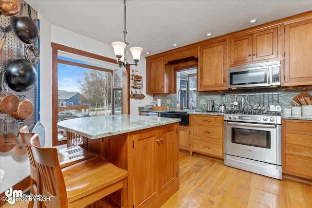 10613 Washington Cir, Anchorage, AK 99515 - kitchen featuring appliances with stainless steel finishes, light wood-style flooring, decorative backsplash, a chandelier, and recessed lighting