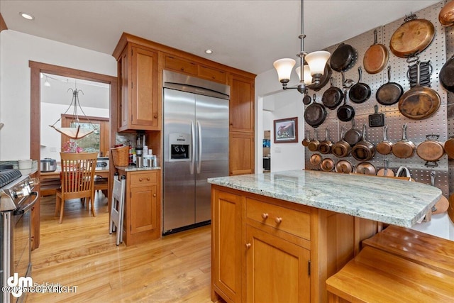10613 Washington Cir, Anchorage, AK 99515 - kitchen with stainless steel appliances, light wood finished floors, a chandelier, light stone countertops, and brown cabinetry