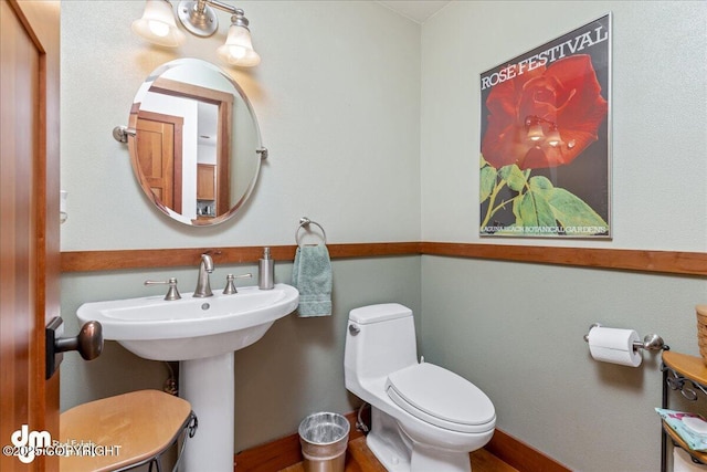 10613 Washington Cir, Anchorage, AK 99515 - half bath with toilet, wood finished floors, a sink, and baseboards