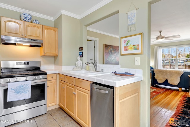 1008 Cordova St, Anchorage, AK 99501 - kitchen featuring under cabinet range hood, stainless steel range with gas stovetop, light brown cabinets, a sink, and ornamental molding