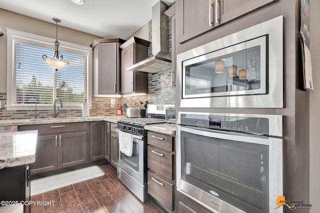 10588 E Nighthawk Cir, Palmer, AK 99645 - kitchen featuring stainless steel appliances, wall chimney range hood, a sink, decorative backsplash, and dark wood finished floors