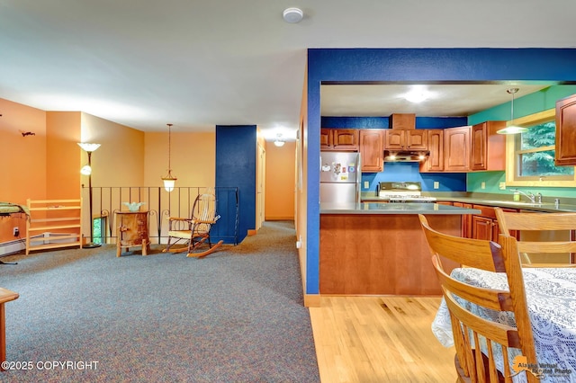 11721 Wranglers Way, Anchorage, AK 99516 - kitchen with freestanding refrigerator, under cabinet range hood, range, pendant lighting, and brown cabinetry