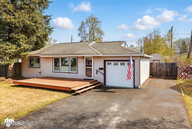 ranch-style home featuring an attached garage, driveway, a wooden deck, and a shingled roof
