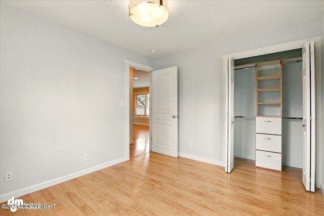 unfurnished bedroom with light wood-type flooring, baseboards, and a closet