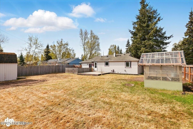 back of property featuring an outdoor structure, a greenhouse, and a deck