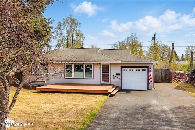 ranch-style house featuring an attached garage, asphalt driveway, roof with shingles, and a wooden deck