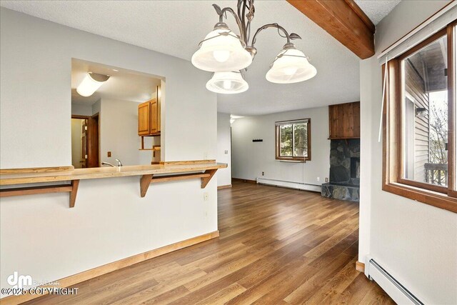 kitchen featuring baseboard heating, a kitchen breakfast bar, wood finished floors, and a fireplace