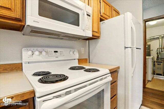 kitchen featuring white appliances, brown cabinetry, light countertops, and wood finished floors