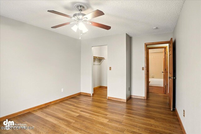 unfurnished bedroom featuring wood finished floors, baseboards, a textured ceiling, and a closet