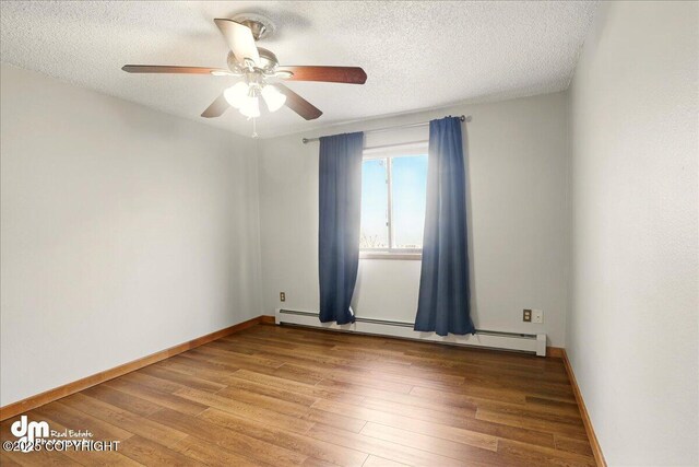 empty room with baseboard heating, light wood-type flooring, a ceiling fan, a textured ceiling, and baseboards