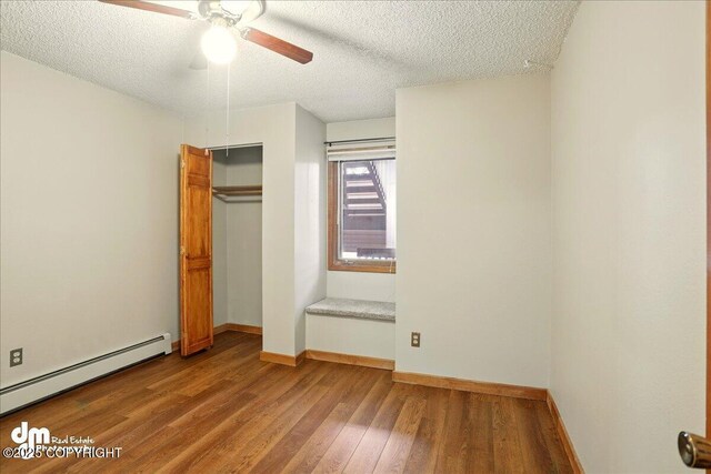 unfurnished bedroom featuring a baseboard radiator, a textured ceiling, wood finished floors, baseboards, and a closet