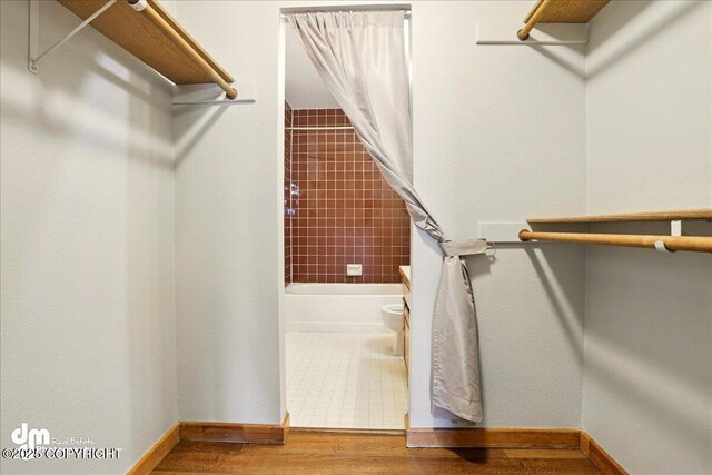 walk in closet with wood finished floors
