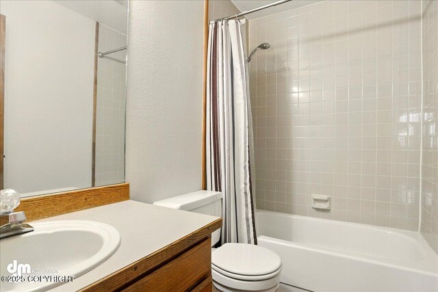 bathroom with toilet, shower / bathtub combination with curtain, vanity, and a textured wall