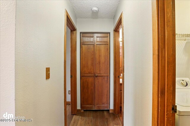 hall featuring dark wood-style flooring, a textured wall, and a textured ceiling