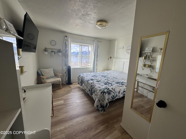 bedroom with a textured ceiling and wood finished floors