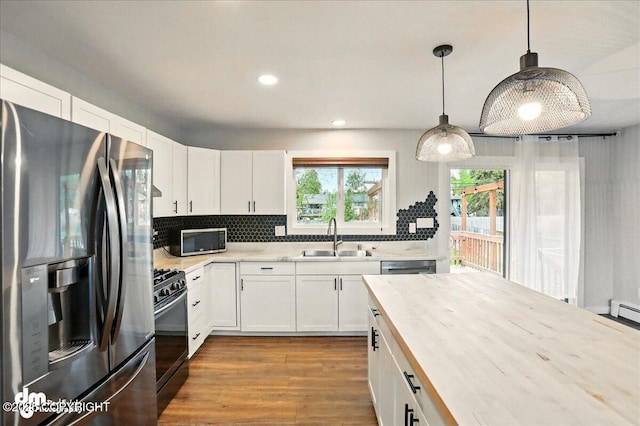 1831 S Salem Dr, Anchorage, AK 99508 - kitchen with stainless steel appliances, a sink, wood finished floors, decorative backsplash, and white cabinets