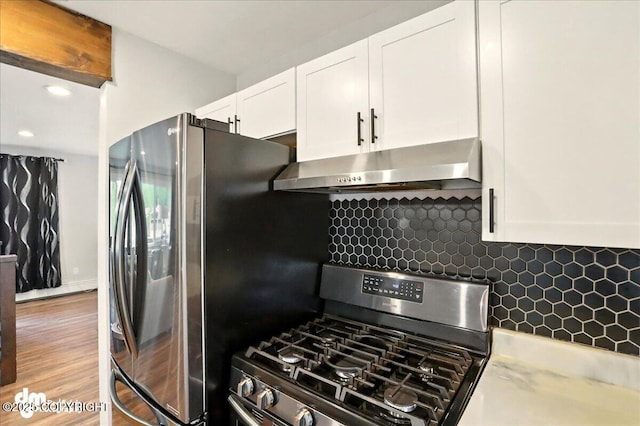 1831 S Salem Dr, Anchorage, AK 99508 - kitchen featuring appliances with stainless steel finishes, range hood, white cabinets, decorative backsplash, and wood finished floors