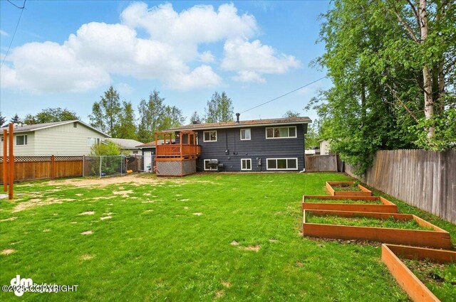 1831 S Salem Dr, Anchorage, AK 99508 - back of property with a vegetable garden, central air condition unit, and a wooden deck