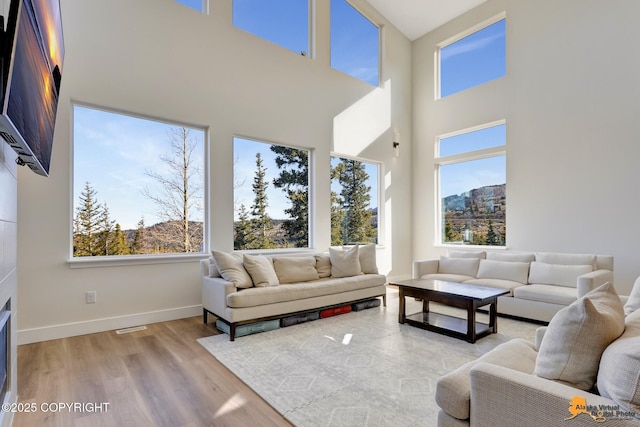 8236 Byron Dr, Anchorage, AK 99516 - living area featuring plenty of natural light, a towering ceiling, wood finished floors, and baseboards