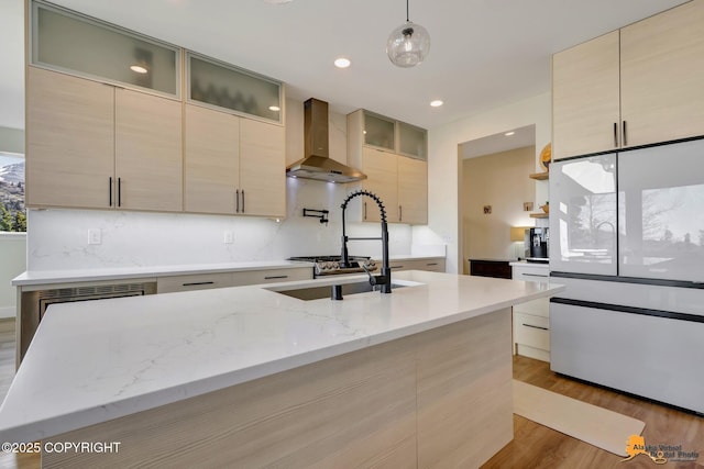 8236 Byron Dr, Anchorage, AK 99516 - kitchen featuring wall chimney exhaust hood, modern cabinets, light wood-style floors, light stone countertops, and pendant lighting