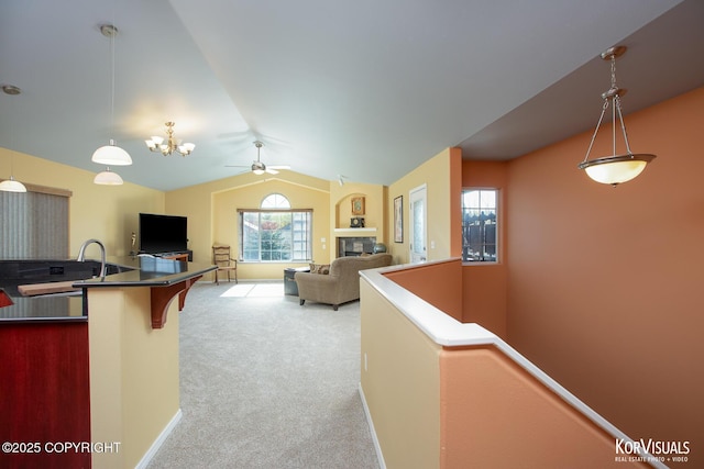 3025 Seclusion Cove Dr # 43, Anchorage, AK 99515 - kitchen with carpet, vaulted ceiling, a ceiling fan, a fireplace, and pendant lighting