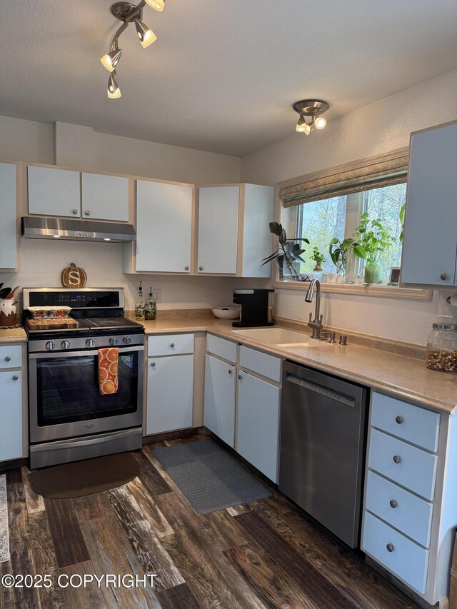 981 E Susitna Dr, Wasilla, AK 99654 - kitchen featuring stainless steel appliances, under cabinet range hood, dark wood finished floors, light countertops, and white cabinetry