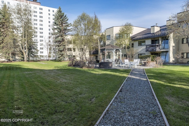 view of property's community featuring a gazebo, a lawn, and a patio